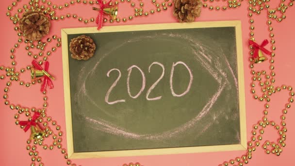 Een mensenhand wist 2020 uit op een zwart bord en schrijft het einde. — Stockvideo