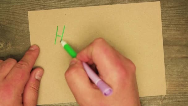 A male hand writes Happy New Year with a green felt-tip pen on a cardboard sheet — Stock Video