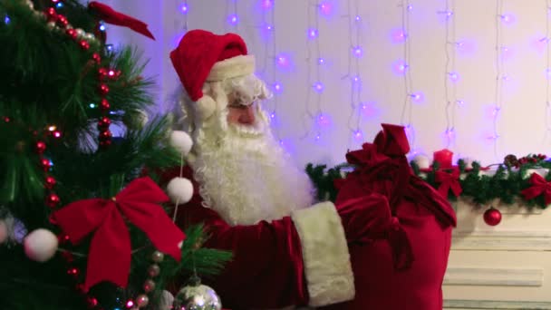 Der Weihnachtsmann hält eine Tüte voller Geschenke in der Hand, begutachtet und bewertet sie. — Stockvideo
