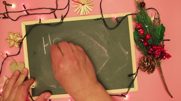 Mano masculina está escribiendo unas felices vacaciones en tiza en una tableta negra. — Vídeo de stock