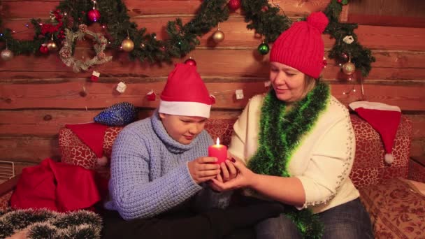 Mama i syn czule trzymają czerwoną świąteczną świeczkę. — Wideo stockowe