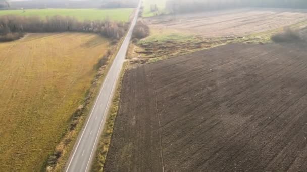 Vuelo rápido y descenso a lo largo del camino hacia un campo agrícola con fertilizante — Vídeos de Stock