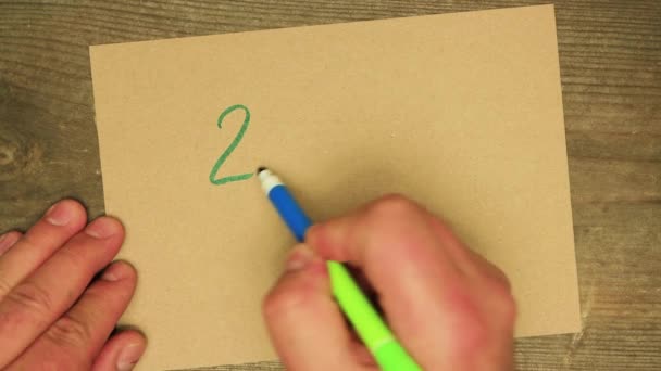 Uma mão masculina escreve o final 2020 com uma caneta azul com ponta de feltro em uma folha de papelão. — Vídeo de Stock