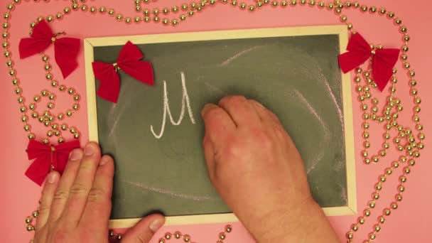 De mannelijke hand schrijft Merry Xmas op een zwarte tablet. — Stockvideo