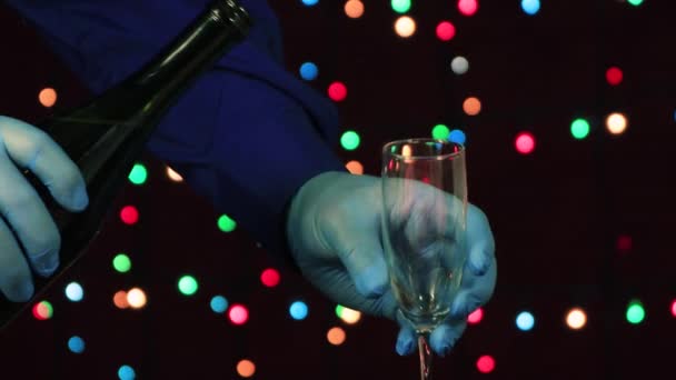Mężczyzna ręce, w rękawiczkach medycznych, wlać szampana do szklanki zbliżenie. — Wideo stockowe
