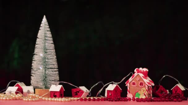 白色的树，红色的花环，黑色背景的姜饼屋. — 图库视频影像