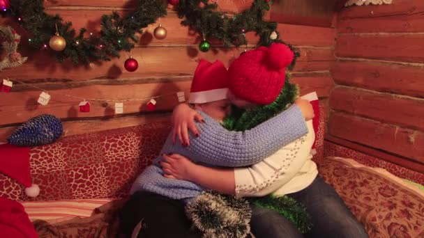 Chico y mamá en gorras rojas se divierten jugando y abrazándose en Navidad. — Vídeos de Stock