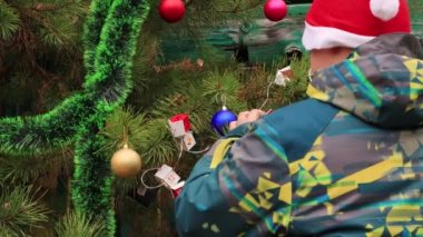 Noel Baba 'nın kırmızı şapkalı çocuğu, arkasını dönüyor, neşeli bir top sallıyor..