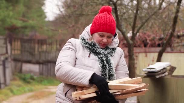 En flicka i röd mössa lägger ut hackade pinnar i händerna närbild. — Stockvideo