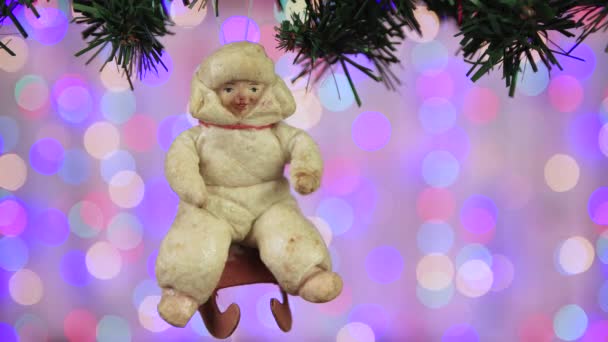 Ein alter Spielzeugjunge auf einem Schlitten hängt in der Silvesternacht an einem Ast und schwankt. — Stockvideo