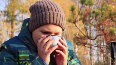 Yakından bir çocuk nazikçe fincandan sıcak çay içiyor..