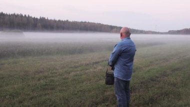 Kotlu bir adam sisli yeşil bir çayırda duruyor.. 