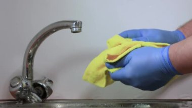 Eldivenli erkek eller turuncu mandalinayı sarı havluyla siliyor..