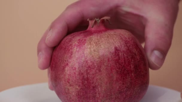 En mans hand förvandlar långsamt ett rött granatäpple på en tallrik. — Stockvideo