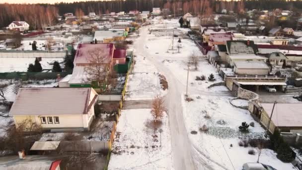 Vlucht over een besneeuwde weg in een klein dorp met huizen met één verdieping. — Stockvideo