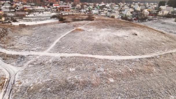 Alto volo su un campo innevato dietro il quale si trova un villaggio. — Video Stock