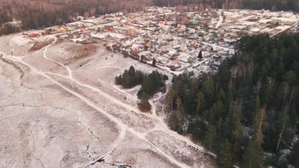 Vista aérea de uma aldeia coberta de neve na borda da floresta. — Vídeo de Stock
