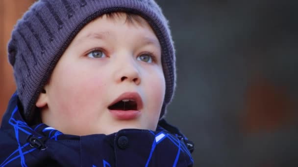 Портрет щасливого хлопчика в куртці і капелюсі, дивлячись вгору в сторону . — стокове відео
