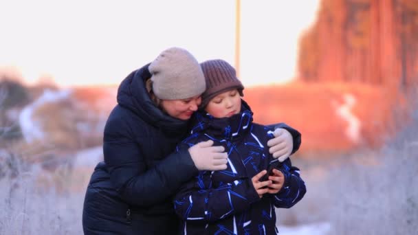 Портрет щасливої мами з сином обіймає і дивиться по телефону . — стокове відео