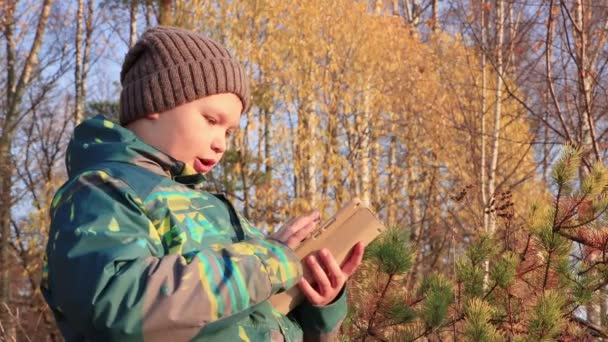 Chłopiec w kapeluszu i kurtce korzysta z Internetu na tablecie. — Wideo stockowe