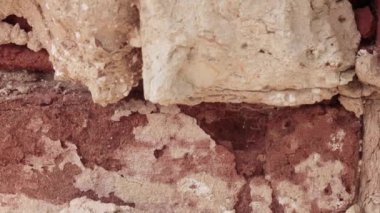 Kırılmış kırmızı tuğla duvar, beyaz alçıyla yakın plan..