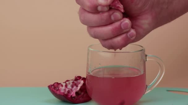En man klämmer juicen från ett granatäpple till ett glas.. — Stockvideo
