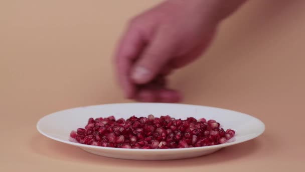 Las manos masculinas muestran semillas de granada maduras en un plato. — Vídeos de Stock