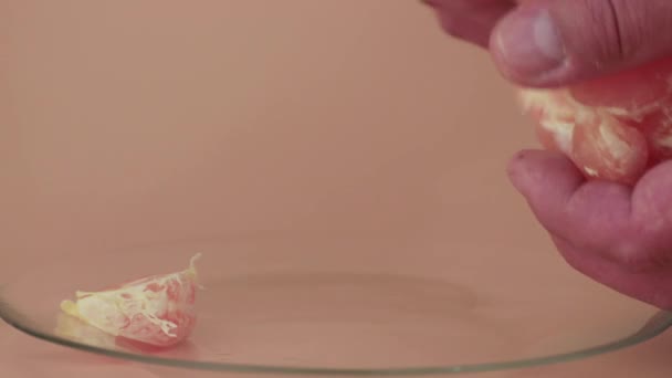 Una mano de hombre coloca lentamente las rebanadas de mandarina en el plato. — Vídeos de Stock