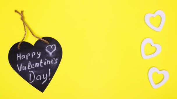 A black heart with an inscription dances on a yellow surface. — Stock Video