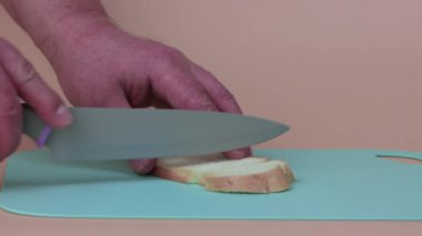 Erkek eller bir parça beyaz ekmeği dilimlere ayırır.. 