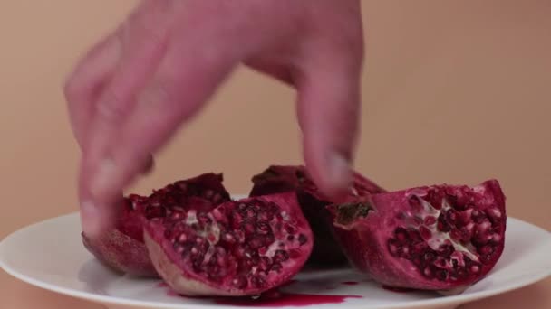 Una mano di uomo lentamente tira fuori fette di melograno su un piatto. — Video Stock