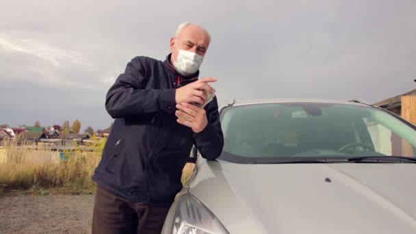 Un hombre de negocios con una máscara está contando facturas apoyadas en su auto.. — Vídeo de stock