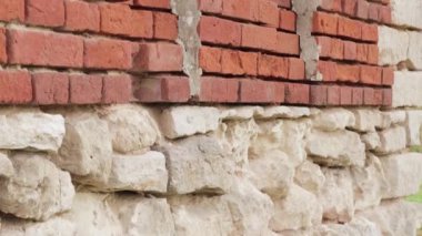 Duvarda beyaz taş duvarlar ve yıkılan kırmızı tuğlalar var..