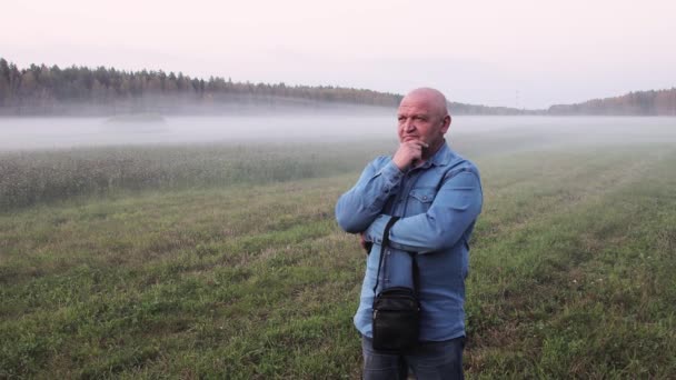 Un homme en jean se tient dans un épais brouillard et pense aux affaires. — Video