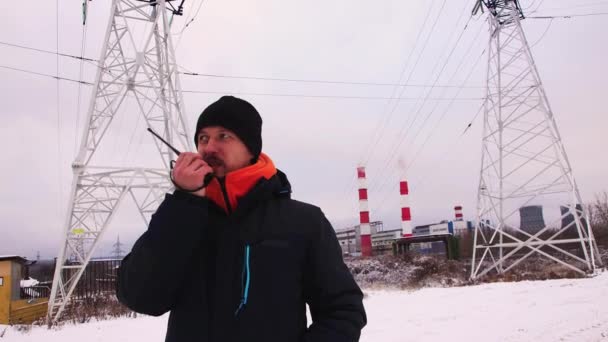 Primer plano Hombre caucásico habla en un walkie-talkie, contra un cielo gris. — Vídeos de Stock