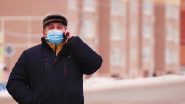 En maskerad man talar i telefon under coronavirus pandemin. — Stockvideo