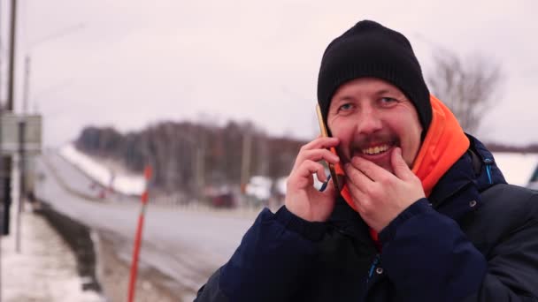 Vit man ler på nära håll och pratar i telefon. — Stockvideo