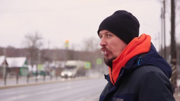 Kaukasischer junger Mann mit Schnurrbart und Bart spuckt auf der Straße und raucht. — Stockvideo