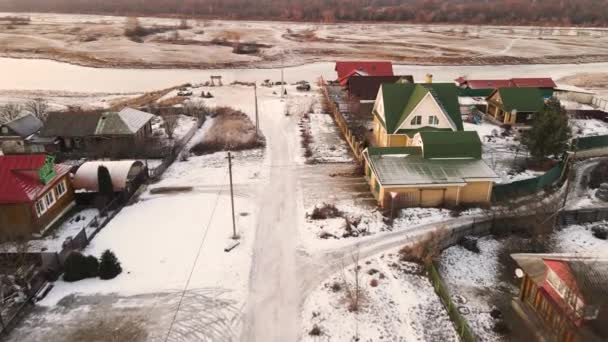 Uitzicht vanuit de lucht op een besneeuwde weg in een dorp met huizen met één verdieping. — Stockvideo