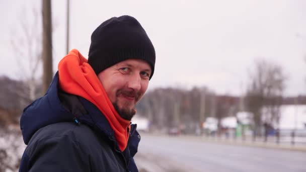 Kaukasische jongeman met snor en baard kijkt vooruit en glimlacht. — Stockvideo
