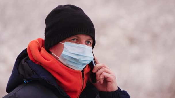 Um homem mascarado fala ao telefone durante a pandemia do coronavírus. — Vídeo de Stock