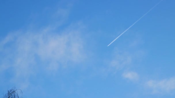 Ένα αεροπλάνο πετάει ανάμεσα στα σύννεφα αφήνοντας ένα λευκό ίχνος. — Αρχείο Βίντεο