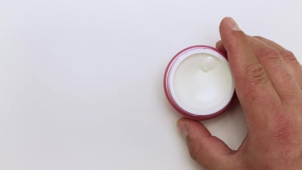 Una mano di uomo tiene e fa roteare un vaso di crema. — Video Stock