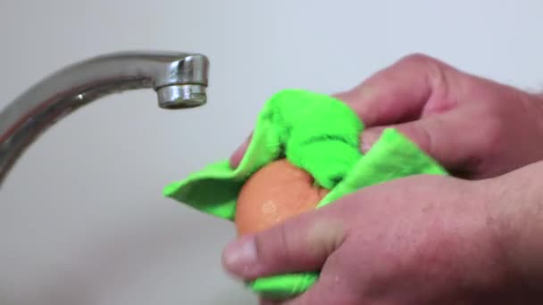 Las manos masculinas secan la mandarina amarilla con una toalla verde. — Vídeo de stock