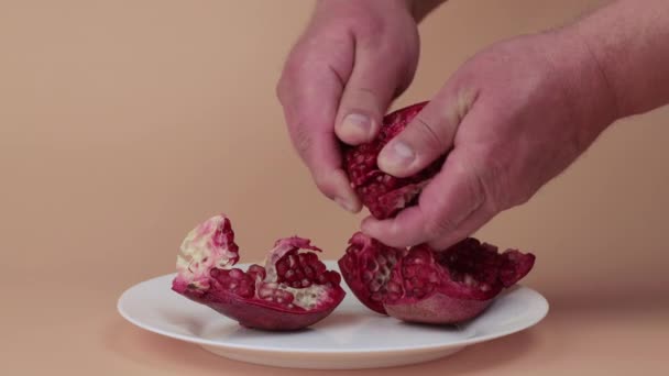 Mãos masculinas suavemente descascar os grãos em uma fatia de romã vermelha — Vídeo de Stock