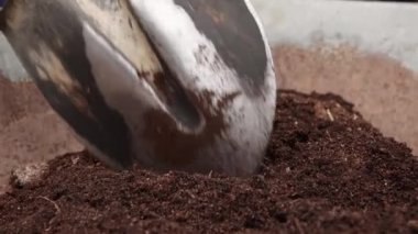 Yakın plan kürek, el arabasında verimli gübreleri yavaşça karıştırıyor..