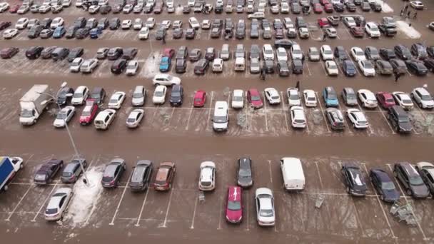 Cars are standing in straight rows in the parking lot, people are walking. — Video