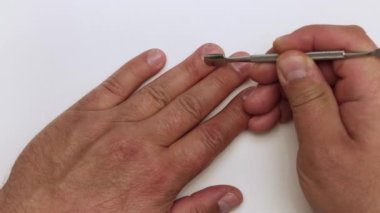 Yakın plan kazıyıcı, bir adamın elinin yüzük parmağından tırnak derisini söker..