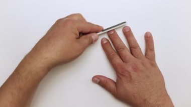 Mans elleri plastik bir tırnak törpüsüyle dikkatlice işliyor..