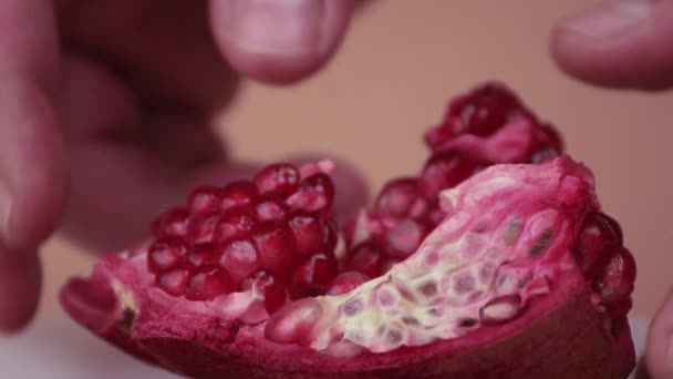 Les mains mâles séparent délicatement les graines mûres du coin de grenade rouge. — Video